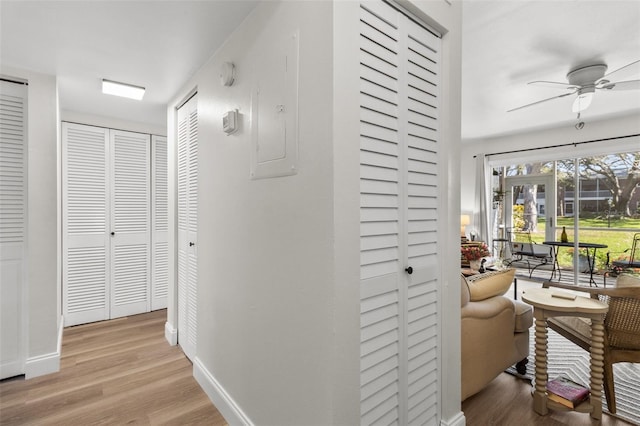 corridor with electric panel and light hardwood / wood-style floors