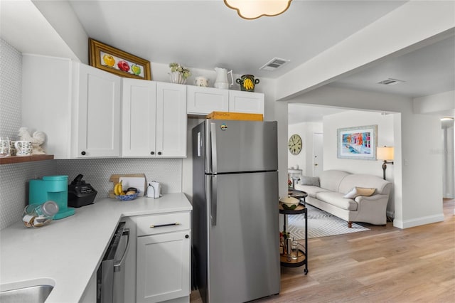 kitchen with sink, light wood-type flooring, stainless steel appliances, decorative backsplash, and white cabinets