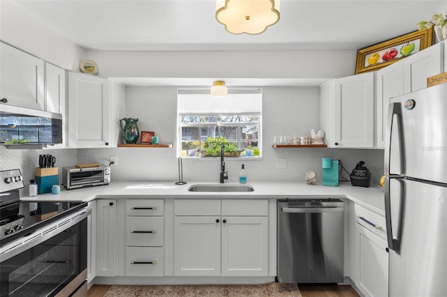 kitchen featuring white cabinetry, sink, backsplash, and appliances with stainless steel finishes