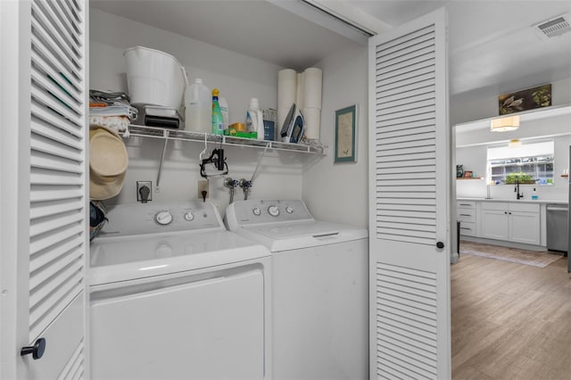 washroom with light hardwood / wood-style floors and washer and dryer