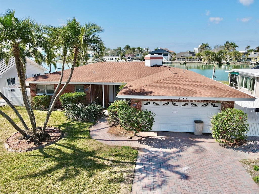 ranch-style home with a garage, a water view, and a front yard