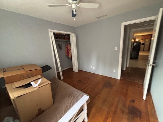 bedroom with a closet, dark hardwood / wood-style floors, and ceiling fan