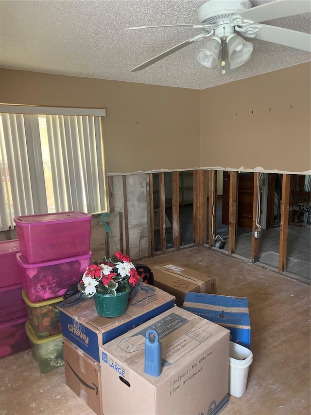 miscellaneous room with ceiling fan and a textured ceiling