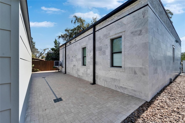 view of side of property with cooling unit and a patio