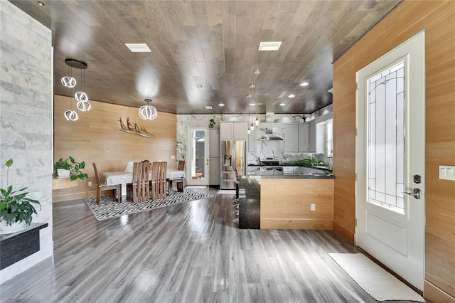 kitchen featuring stainless steel appliances, dark wood-type flooring, a wealth of natural light, and wall chimney exhaust hood