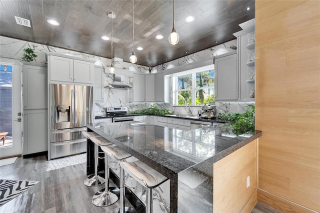 kitchen featuring a breakfast bar, sink, decorative light fixtures, light hardwood / wood-style flooring, and stainless steel appliances