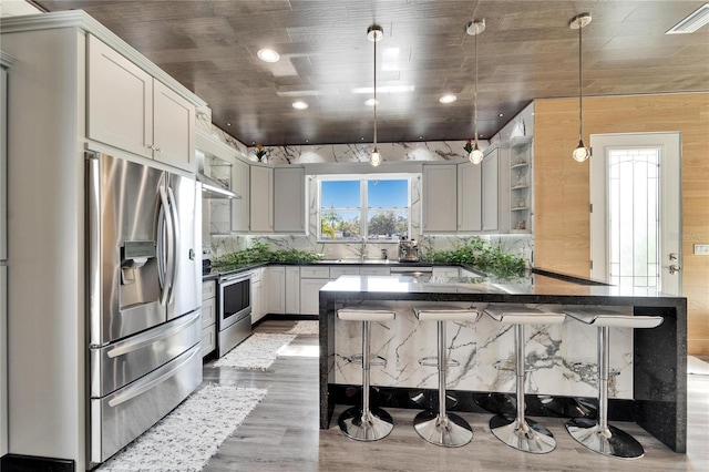 kitchen with a breakfast bar area, hanging light fixtures, stainless steel appliances, dark hardwood / wood-style floors, and white cabinets