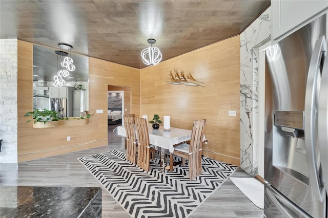 dining space with hardwood / wood-style flooring and wood walls