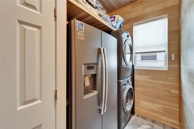 laundry area with stacked washer / drying machine and wood walls