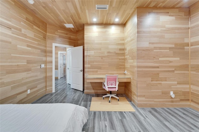 bedroom with wood-type flooring, built in desk, wooden ceiling, and wood walls