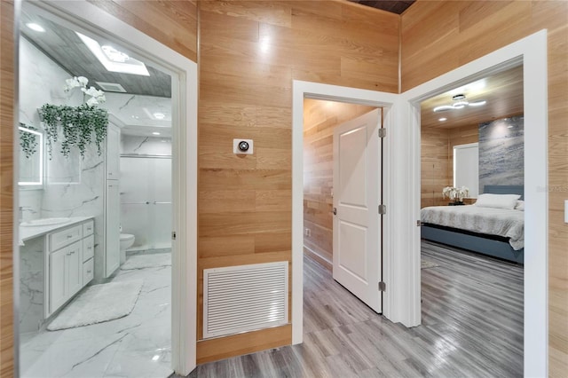 bathroom with hardwood / wood-style flooring, vanity, toilet, and wood walls