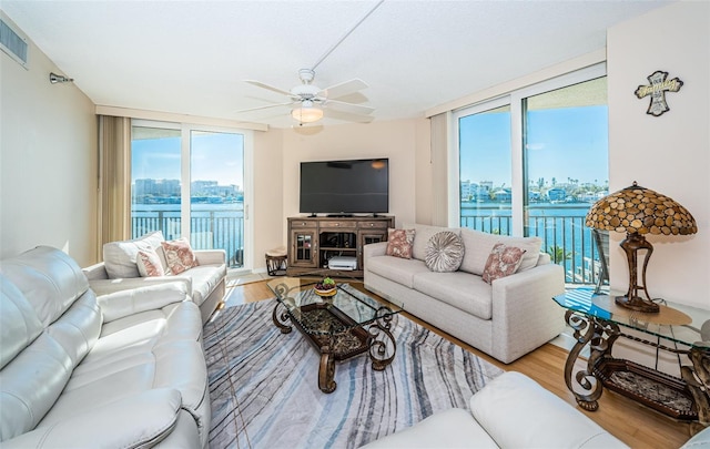 living room featuring expansive windows, ceiling fan, and light hardwood / wood-style floors