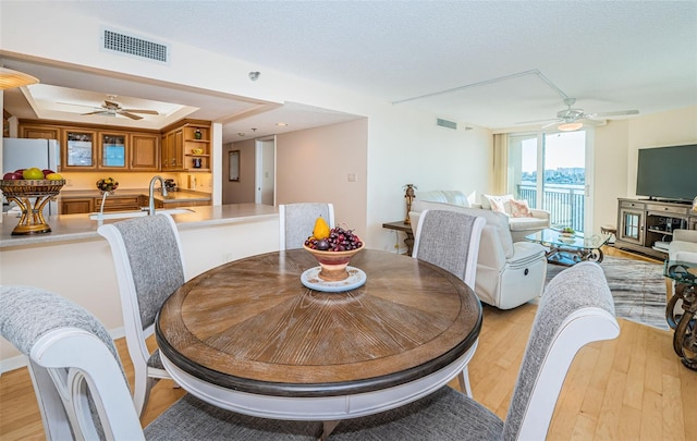 dining area featuring a textured ceiling, ceiling fan, and light hardwood / wood-style flooring