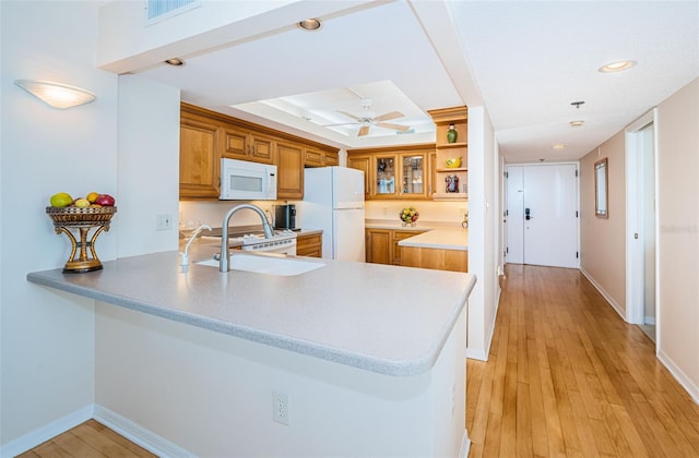 kitchen featuring sink, white appliances, light hardwood / wood-style flooring, ceiling fan, and kitchen peninsula