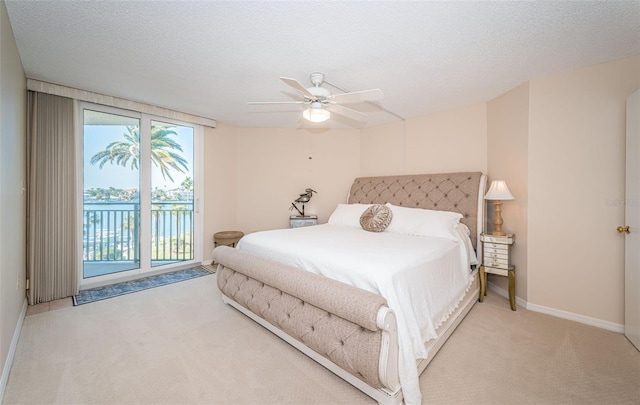 bedroom featuring access to outside, light colored carpet, ceiling fan, a water view, and a textured ceiling