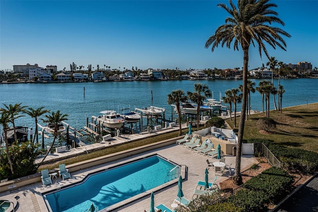 view of swimming pool featuring a water view, a boat dock, and a patio area