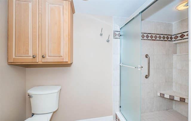 bathroom featuring a shower with shower door and toilet