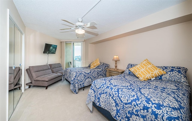 bedroom with carpet floors, access to exterior, ceiling fan, a textured ceiling, and a closet