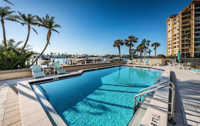 view of swimming pool featuring a water view and a patio area