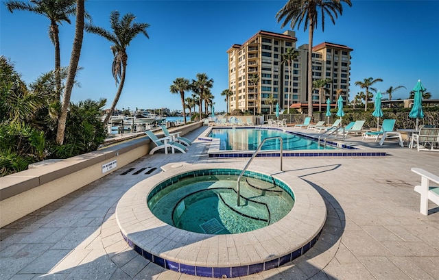 view of swimming pool featuring a hot tub and a patio area