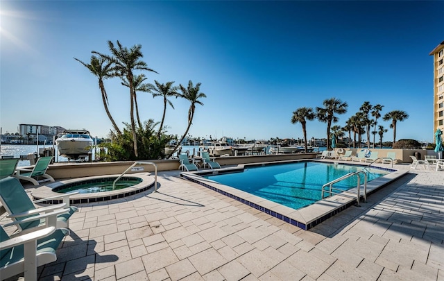 view of pool with a water view, a patio area, and a community hot tub