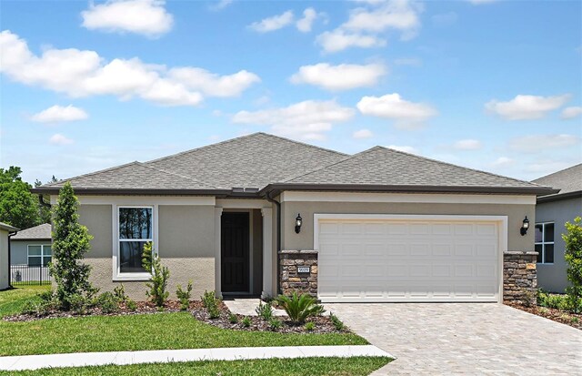 prairie-style home featuring decorative driveway, stone siding, and stucco siding