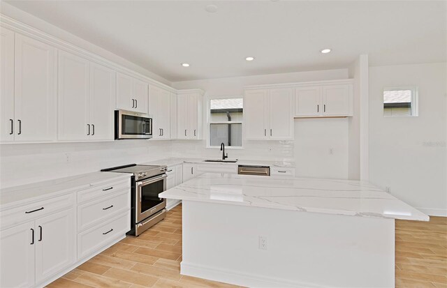kitchen featuring a sink, appliances with stainless steel finishes, white cabinetry, and a wealth of natural light