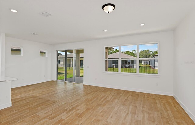 spare room featuring a healthy amount of sunlight, baseboards, and light wood finished floors