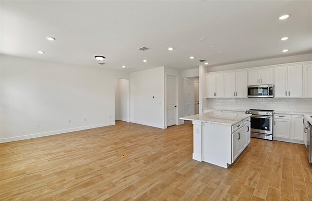 kitchen featuring backsplash, recessed lighting, appliances with stainless steel finishes, and a center island