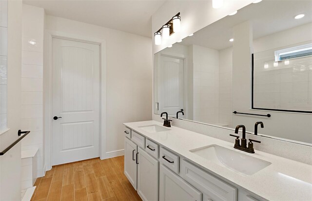full bath with double vanity, recessed lighting, a sink, and wood finished floors