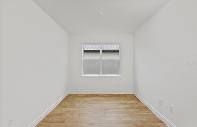 spare room with baseboards and light wood-style flooring