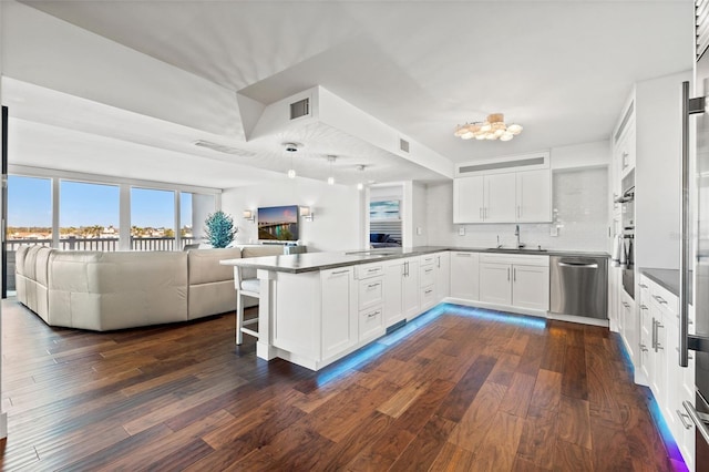 kitchen featuring white cabinetry, sink, stainless steel dishwasher, kitchen peninsula, and dark wood-type flooring