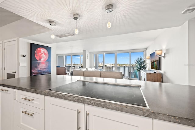 kitchen with hanging light fixtures, white cabinetry, and black electric cooktop