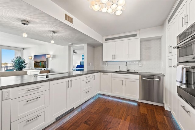 kitchen featuring sink, white cabinetry, dark hardwood / wood-style flooring, stainless steel appliances, and decorative backsplash