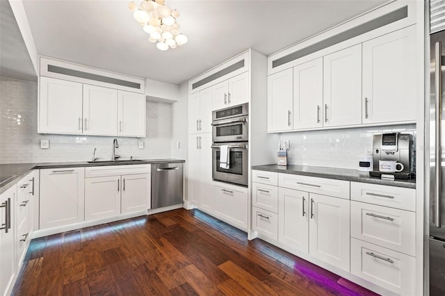 kitchen featuring appliances with stainless steel finishes, sink, dark wood-type flooring, and white cabinets