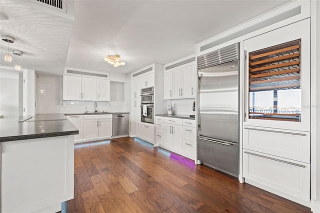 kitchen with dark wood-type flooring, sink, stainless steel appliances, decorative backsplash, and white cabinets