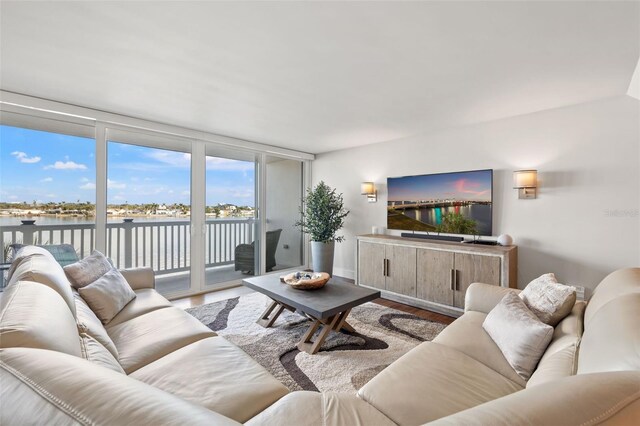 living room featuring wood-type flooring, a wall of windows, and a water view