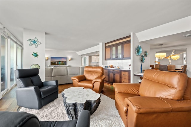 living room with an inviting chandelier, hardwood / wood-style flooring, and indoor bar