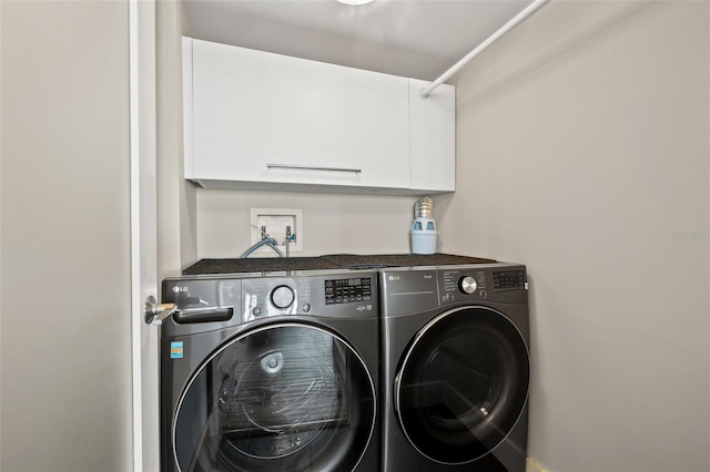 laundry room with washing machine and dryer and cabinets