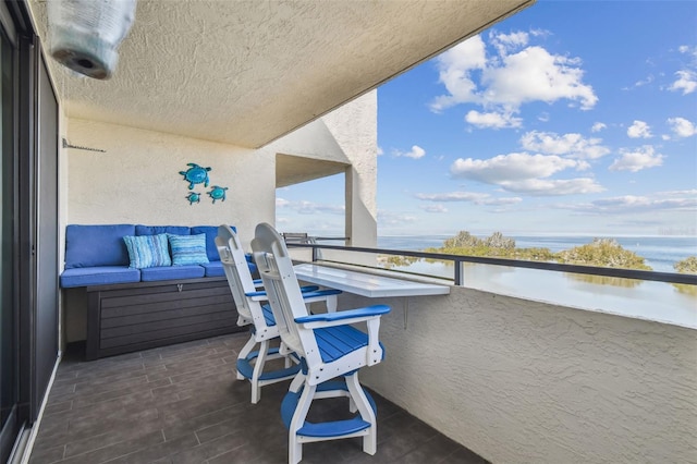 balcony with an outdoor hangout area and a water view