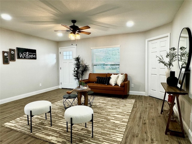 living room featuring ceiling fan, dark hardwood / wood-style floors, and a textured ceiling