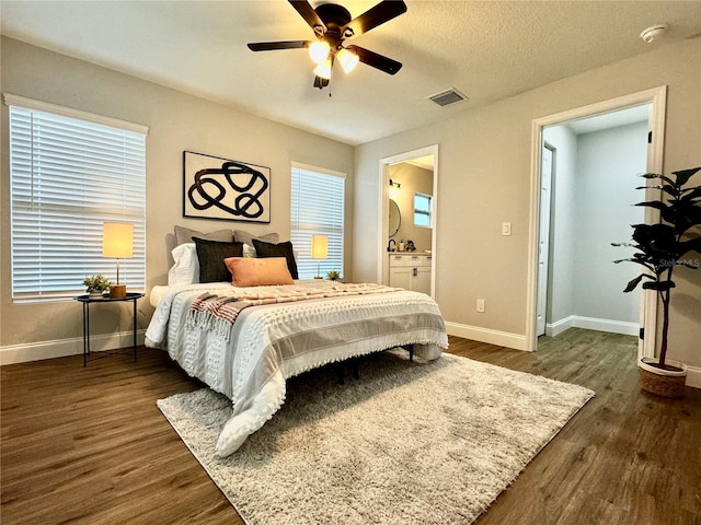 bedroom with ceiling fan, dark wood-type flooring, connected bathroom, and a textured ceiling