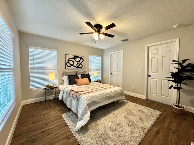 bedroom featuring dark hardwood / wood-style flooring, ceiling fan, and a textured ceiling