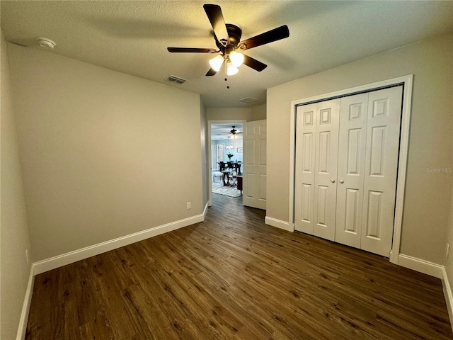 unfurnished bedroom with dark hardwood / wood-style flooring, ceiling fan, a closet, and a textured ceiling