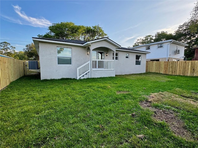 rear view of property with cooling unit and a lawn