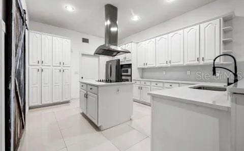 kitchen with sink, appliances with stainless steel finishes, a center island, white cabinets, and island exhaust hood