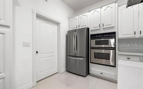 kitchen with appliances with stainless steel finishes, light tile patterned floors, and white cabinets