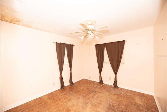 spare room with ceiling fan and baseboards