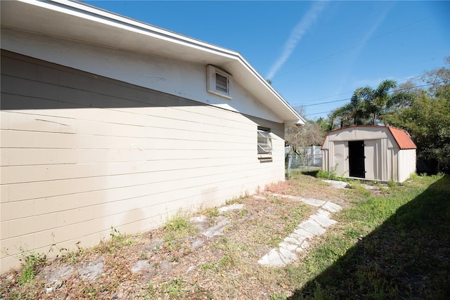 view of side of property with a yard, a shed, an outdoor structure, and fence