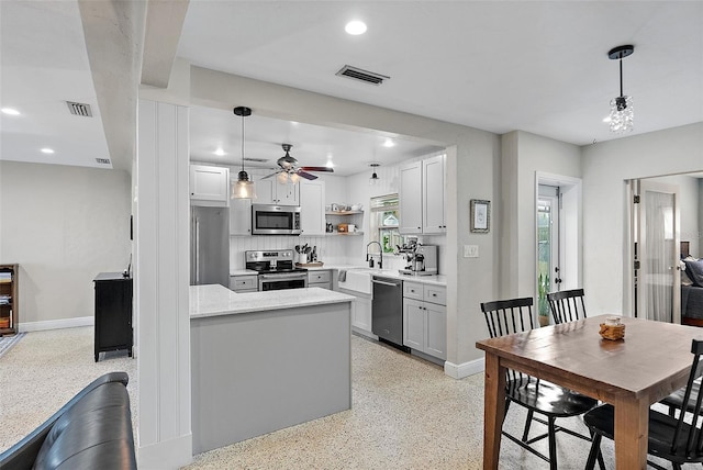 kitchen with sink, ceiling fan, appliances with stainless steel finishes, white cabinets, and decorative light fixtures